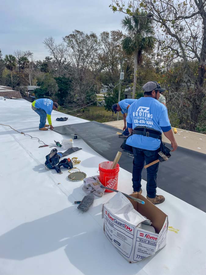 Roofers collaborate to roll out new roofing material on a large commercial flat roof, showcasing teamwork and efficiency.