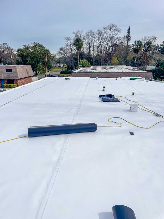 A team of roofers working on a commercial flat roof, showing coordination and teamwork during the roofing installation process.